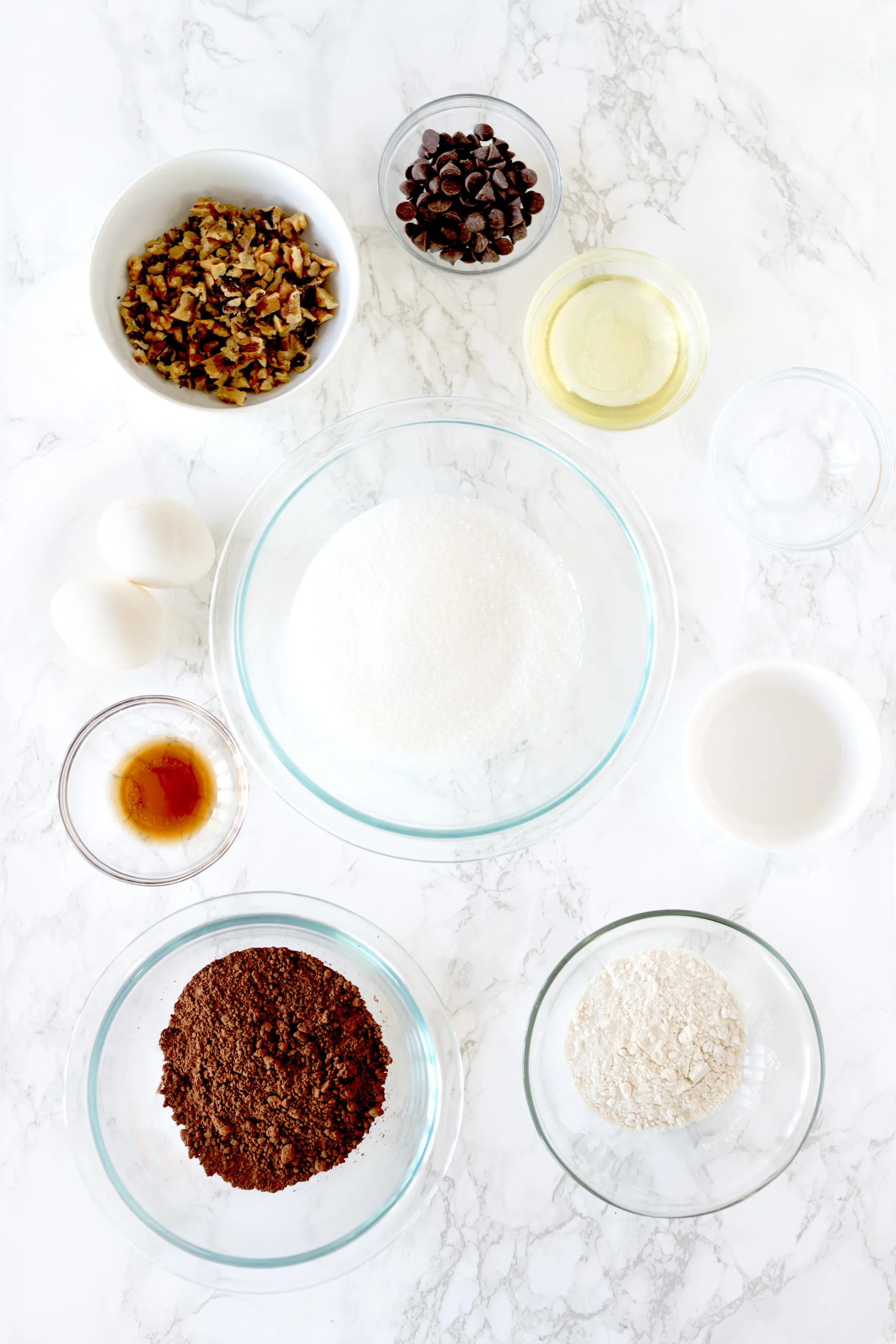 dairy free brownie ingredients in little bowls on a white marble counter
