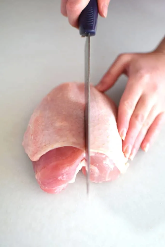 Knife cutting through a whole chicken breast