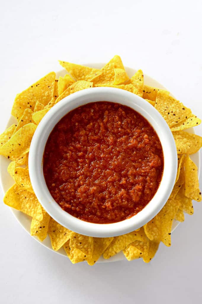 Birds eye view of restaurant style salsa in a bowl surrounded by corn chips