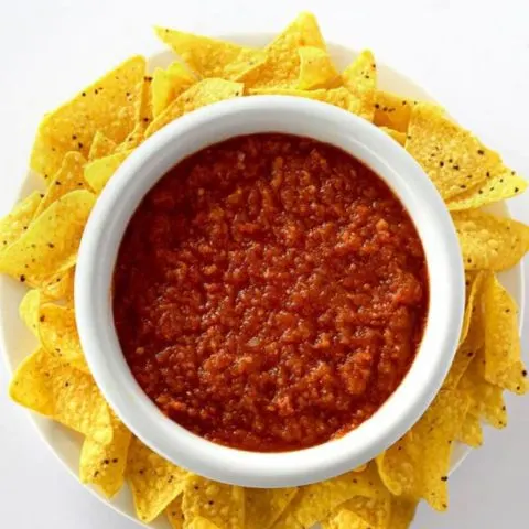 Birds eye view of restaurant style salsa in a bowl surrounded by corn chips