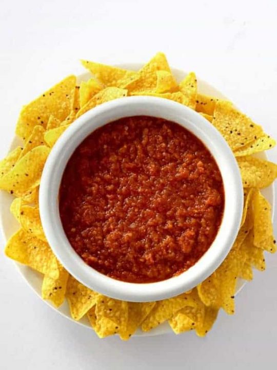 Birds eye view of restaurant style salsa in a bowl surrounded by corn chips