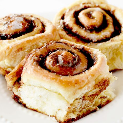 three dairy free cinnamon rolls on a white plate