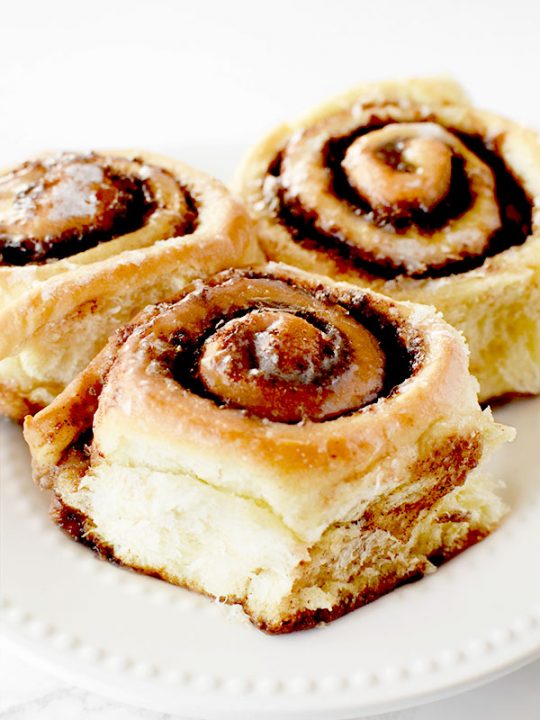 three dairy free cinnamon rolls on a white plate