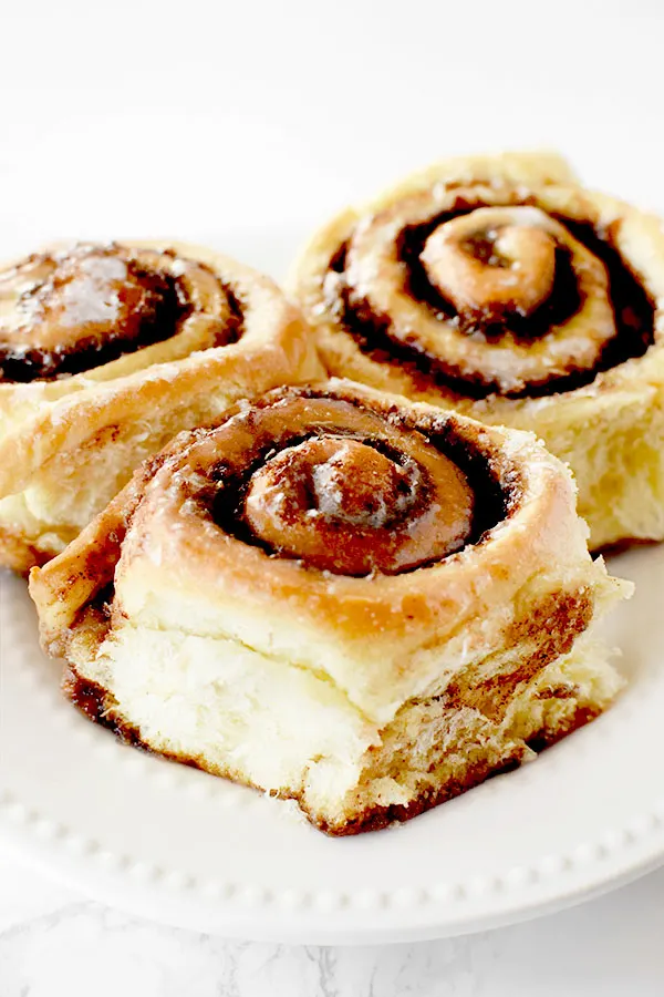 three dairy free cinnamon rolls on a white plate