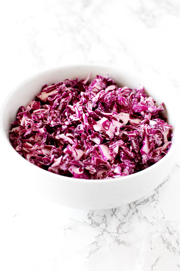 Israeli red cabbage salad in a white bowl on a white marble counter