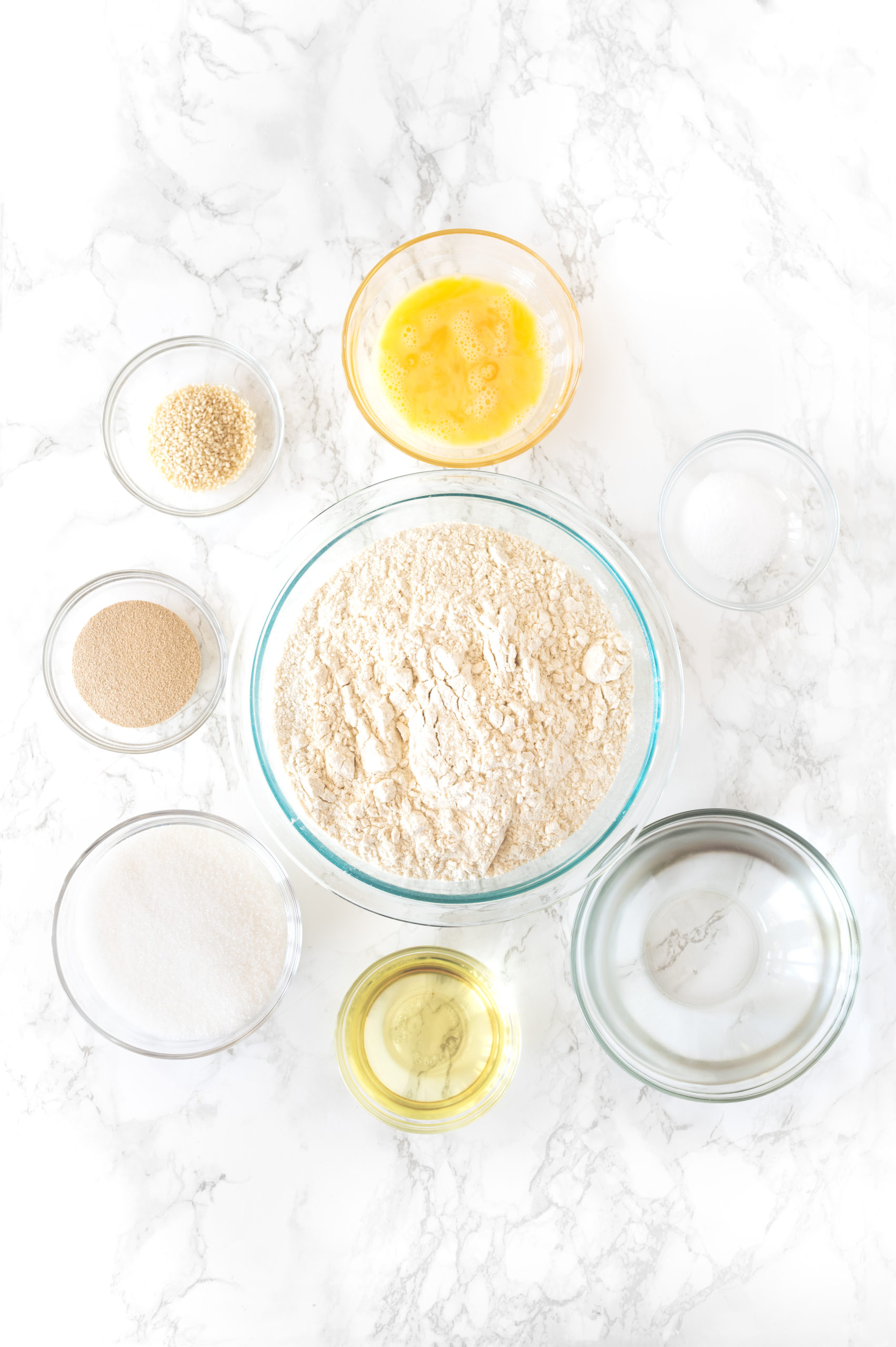 ingredients for challah in glass bowls on a white marble counter