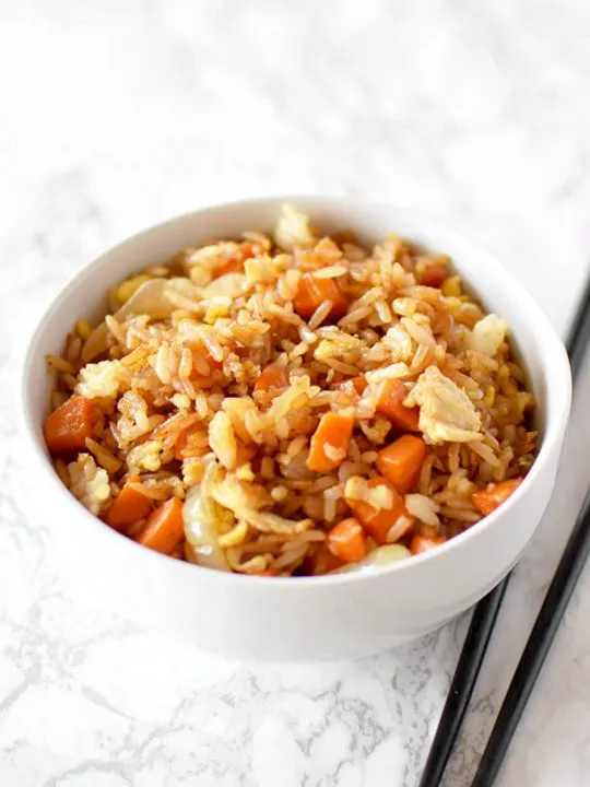 fried rice in a white bowl on a white marble counter