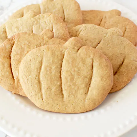 pumpkin spice cookies cut into pumpkin shapes on a white plate