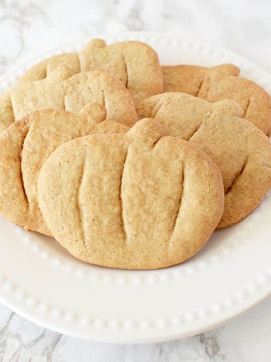 pumpkin spice cookies cut into pumpkin shapes on a white plate