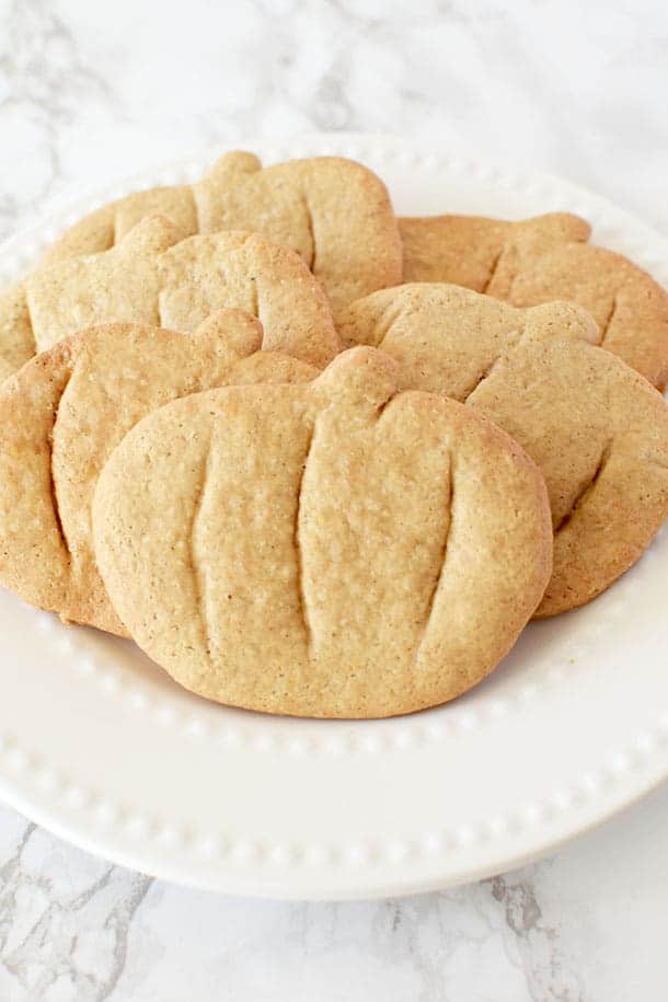 pumpkin spice cookies cut into pumpkin shapes on a white plate