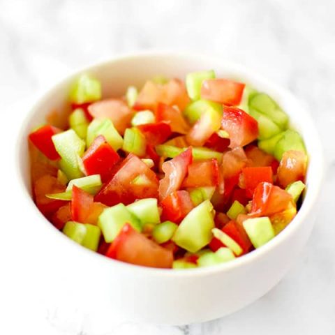 Israeli salad in a white bowl on a white marble counter