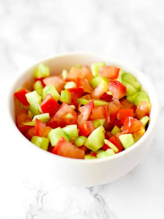 Israeli salad in a white bowl on a white marble counter