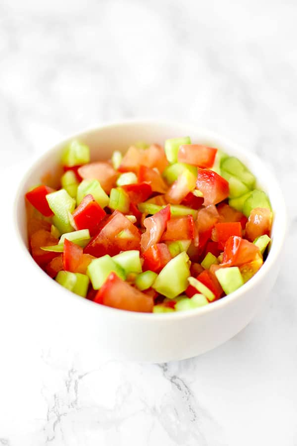 Israeli salad in a white bowl on a white marble counter