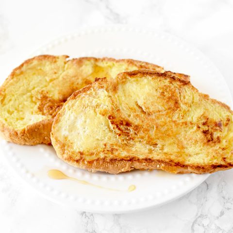 French toast on a white plate on a white marble counter