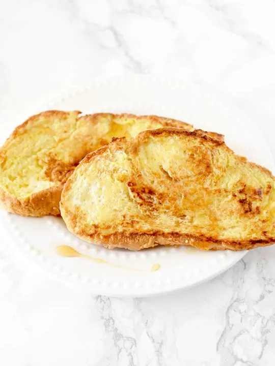 French toast on a white plate on a white marble counter