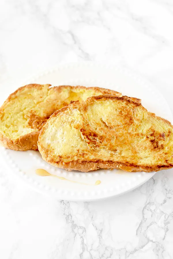 French toast on a white plate on a white marble counter