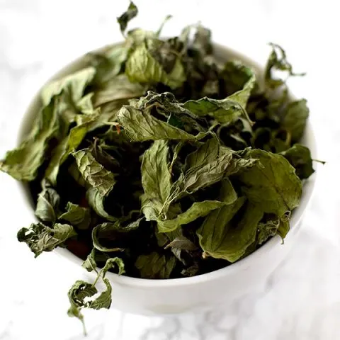 dried mint leaves in a white bowl on a counter