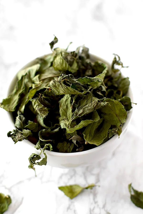 dried mint leaves in a white bowl on a counter