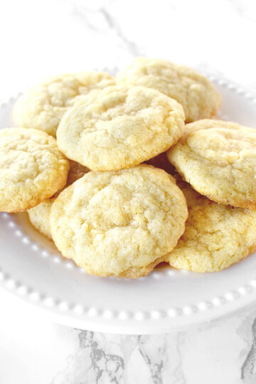 Dairy free sugar cookies piled up on a white plate on a white marble counter