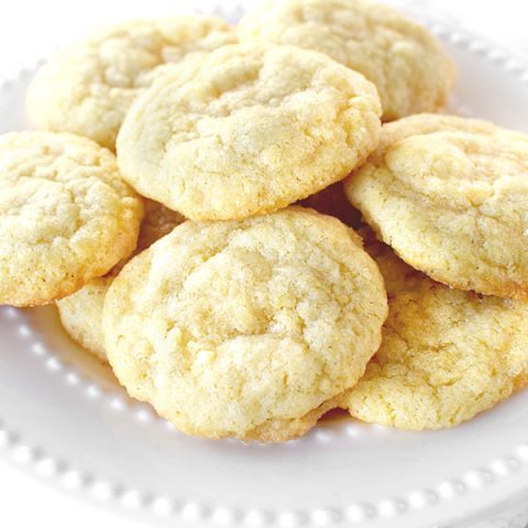 Dairy free sugar cookies piled up on a white plate on a white marble counter