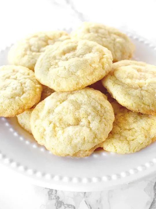 Dairy free sugar cookies piled up on a white plate on a white marble counter