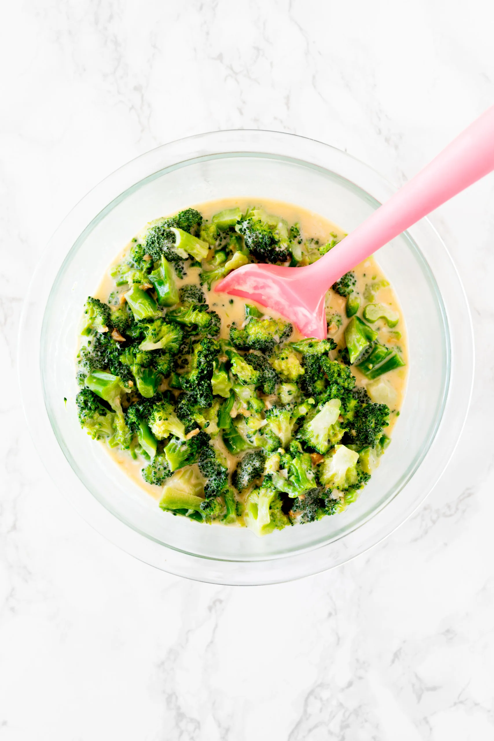 broccoli kugel mixture in a bowl on a white marble counter