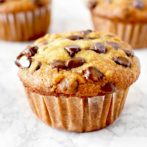 moist three banana chocolate chip muffins on a white marble counter