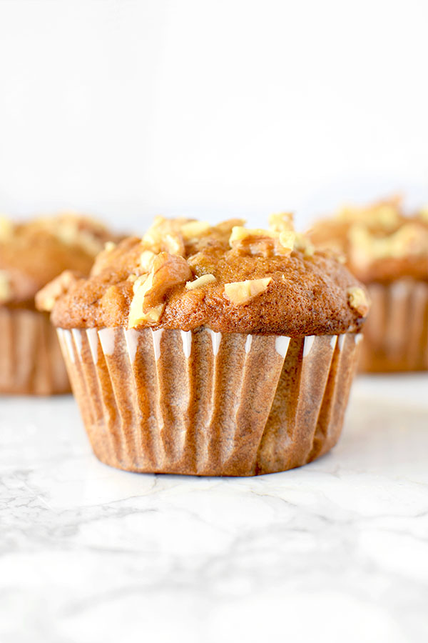 Three banana nut muffins on a white marble counter