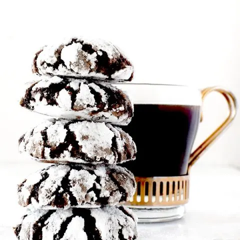 stack of mocha crinkle cookies near a cup of black coffee