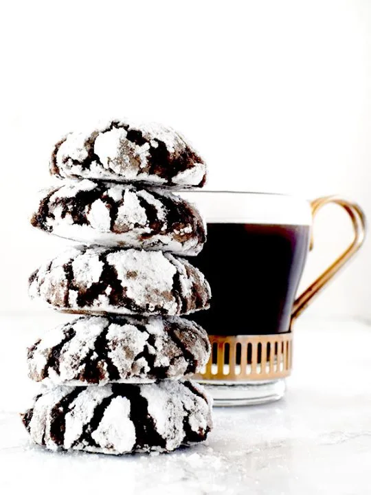 stack of mocha crinkle cookies near a cup of black coffee