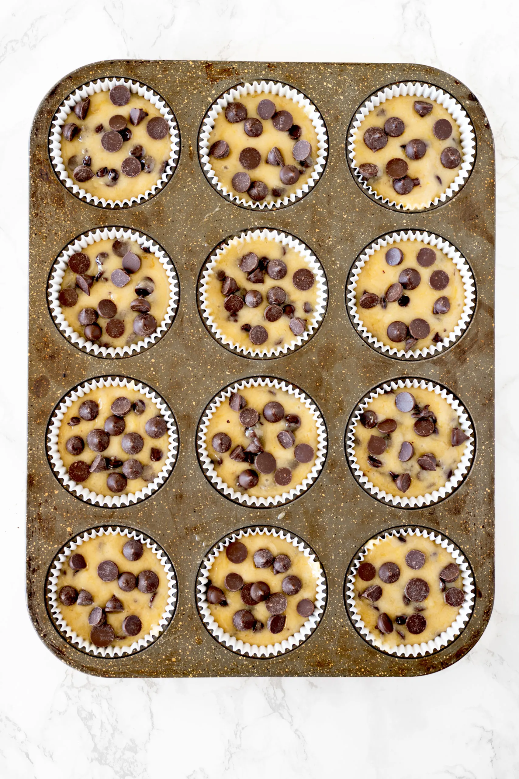 banana chocolate chip muffin batter in a muffin pan
