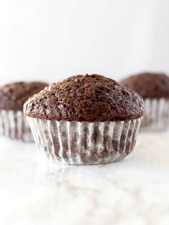 three chocolate muffins on a white counter