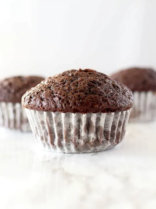 three chocolate muffins on a white counter