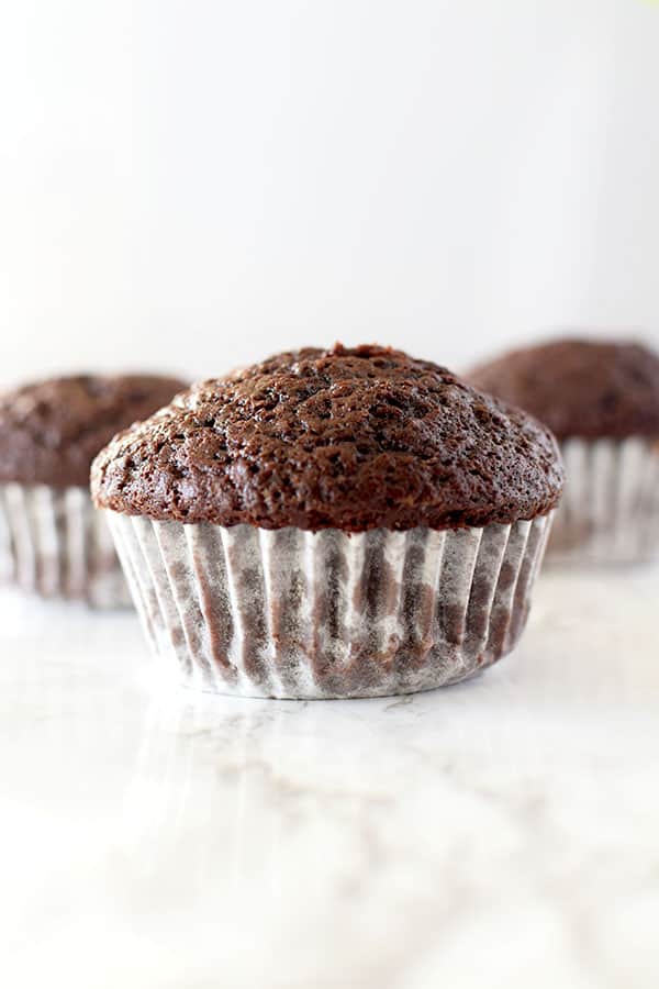 three chocolate muffins on a white counter
