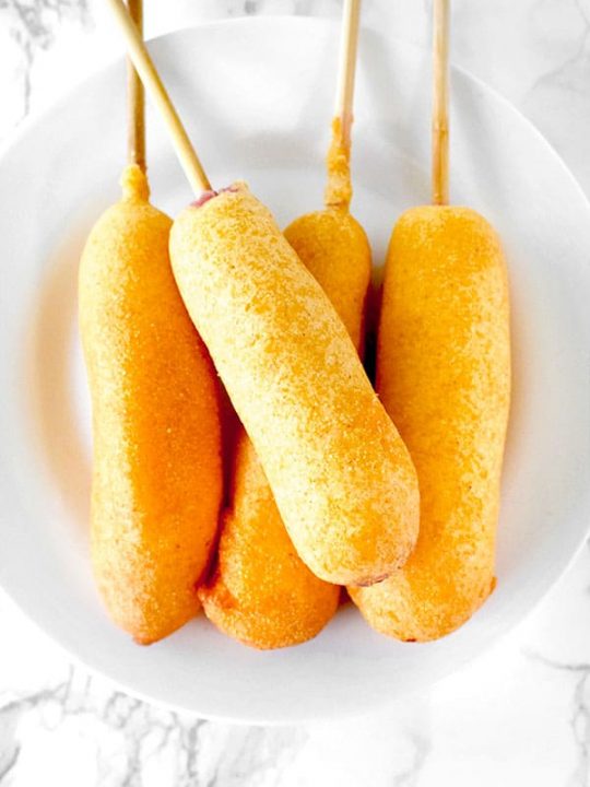 four corn dogs on a white plate