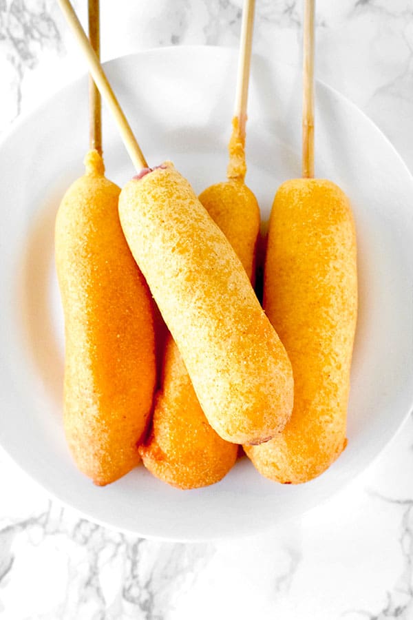 four corn dogs on a white plate