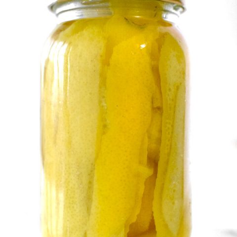 Lemon peals in a jar with vadka on a white marble counter