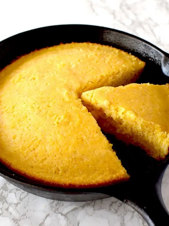 Cornbread in a cast iron skillet with a piece missing