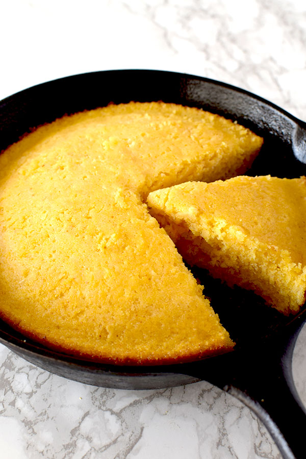 cornbread with oat milk in a cast iron skillet on a white marble counter
