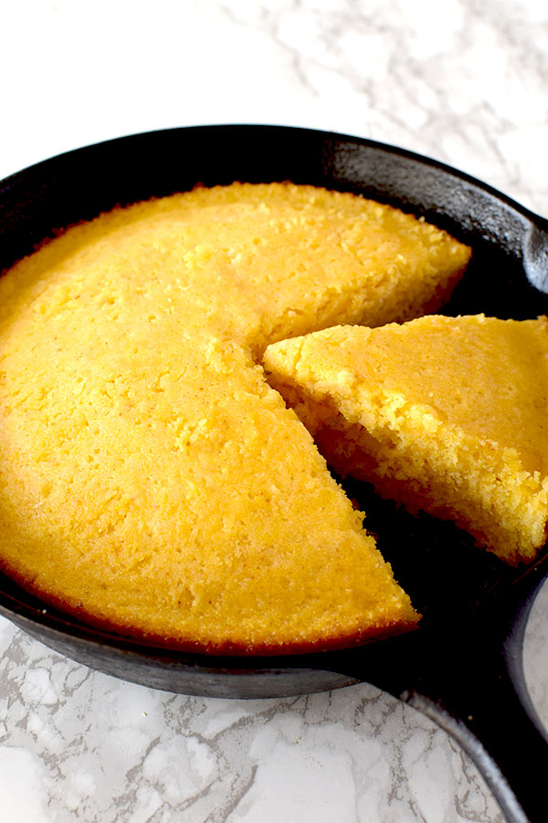 Cornbread in a cast iron skillet with a piece missing