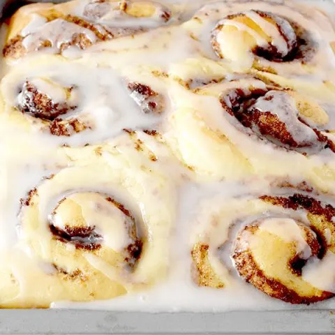 Six glazed no knead cinnamon rolls in a baking pan