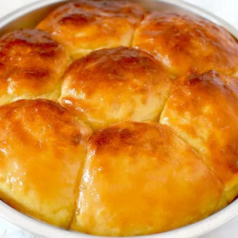 no knead yeast rolls in a round baking pan on a marble counter