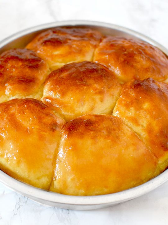 no knead yeast rolls in a round baking pan on a marble counter