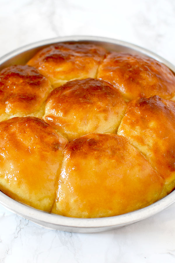 no knead yeast rolls in a round baking pan on a marble counter