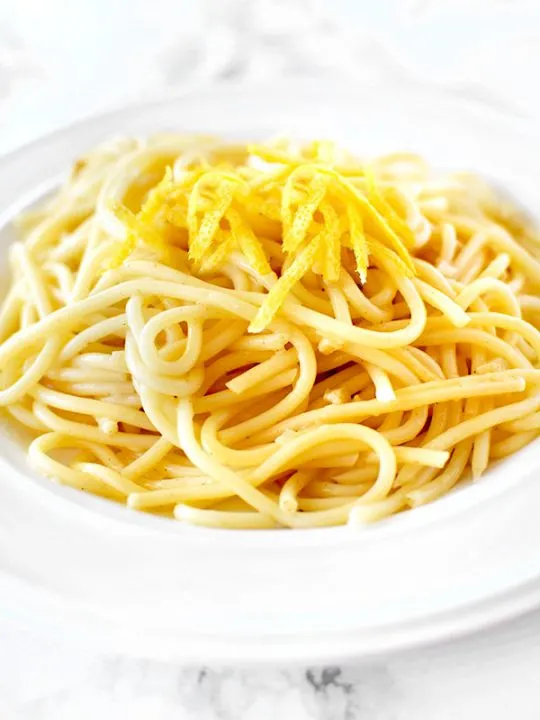 Spaghetti al Limone topped with lemon zest in a white bowl