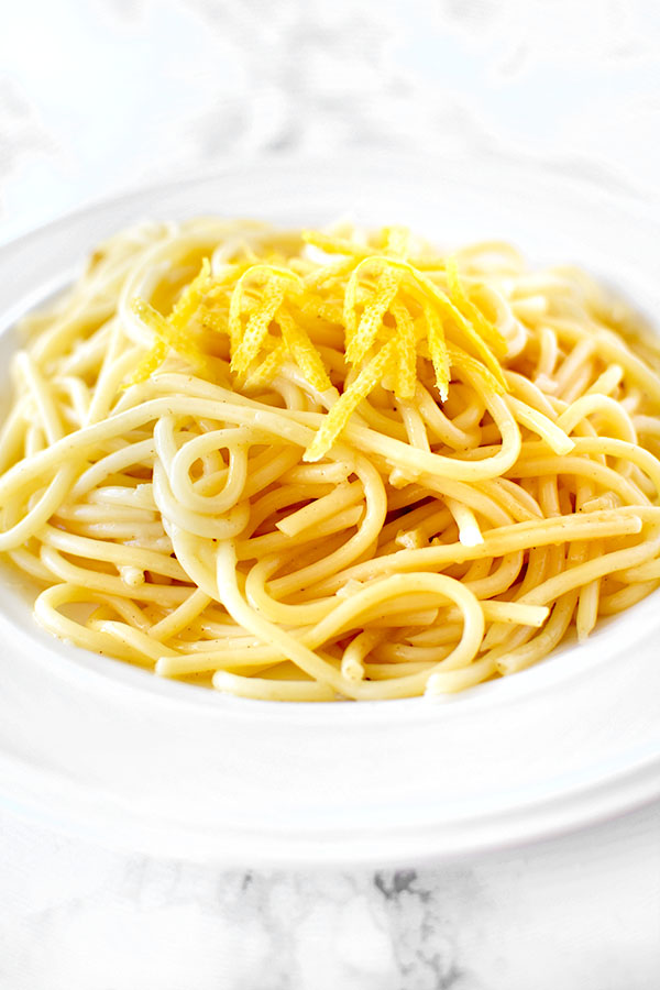 Spaghetti al Limone topped with lemon zest in a white bowl