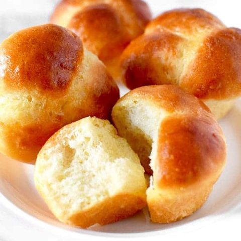 Four cloverleaf rolls on a white plate