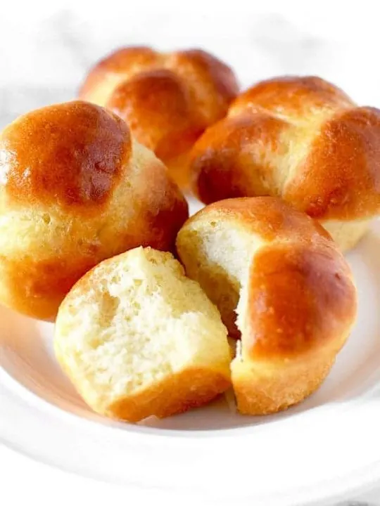 Four cloverleaf rolls on a white plate