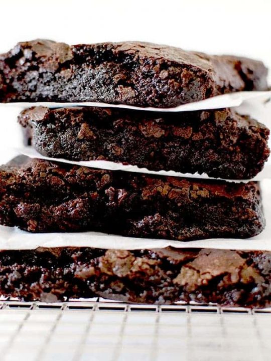 Fudge brownies stacked on a cooling rack