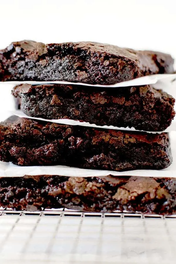 Fudge brownies stacked on a cooling rack